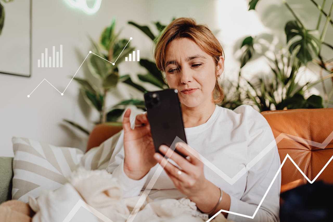 Woman in white long sleeves using smartphone on sofa with graph overlays and house plants.